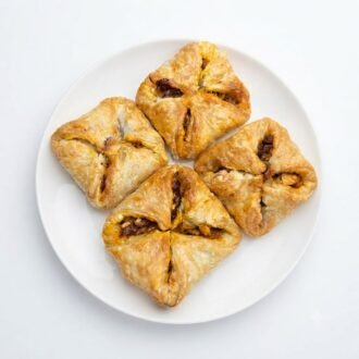 Golden folded puff pastry with filling visible on a white plate.
